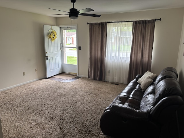 living area with light carpet, baseboards, and a ceiling fan