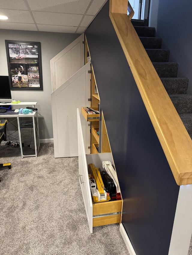 staircase with a paneled ceiling and carpet