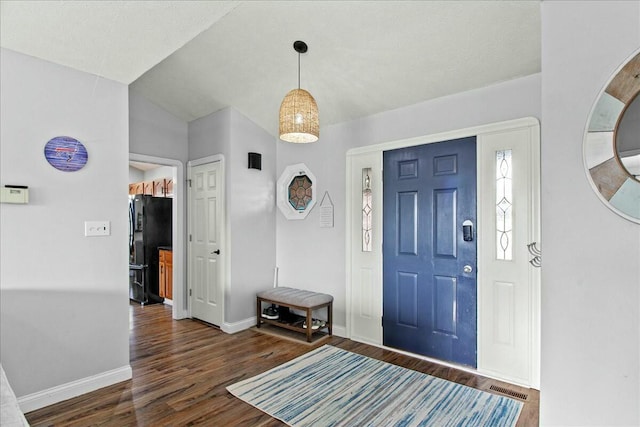 foyer featuring visible vents, vaulted ceiling, baseboards, and wood finished floors