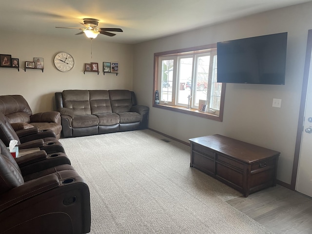 living area featuring ceiling fan, light colored carpet, and baseboards