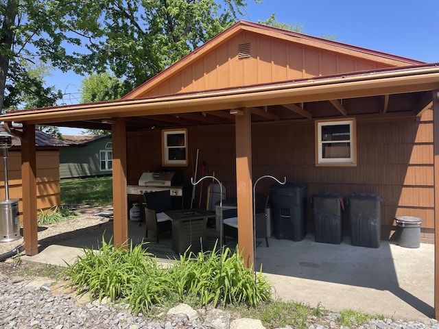 back of property with board and batten siding and a patio