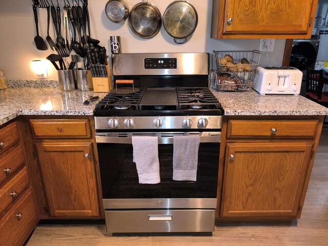 kitchen with stainless steel gas range and light stone countertops