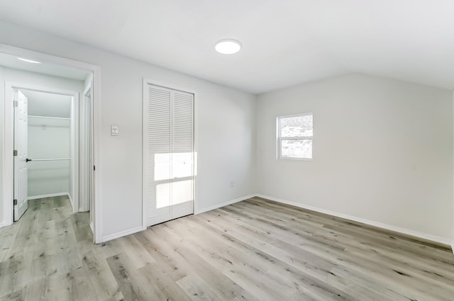 unfurnished bedroom featuring lofted ceiling, light hardwood / wood-style floors, and a closet