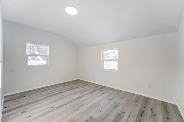 empty room featuring vaulted ceiling and light hardwood / wood-style floors