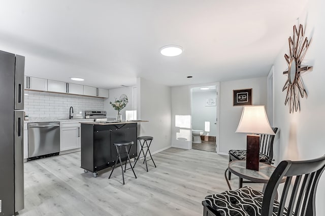 kitchen with white cabinetry, backsplash, a kitchen breakfast bar, a center island, and stainless steel appliances