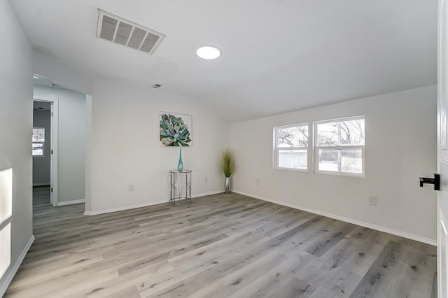 empty room with lofted ceiling and light hardwood / wood-style floors