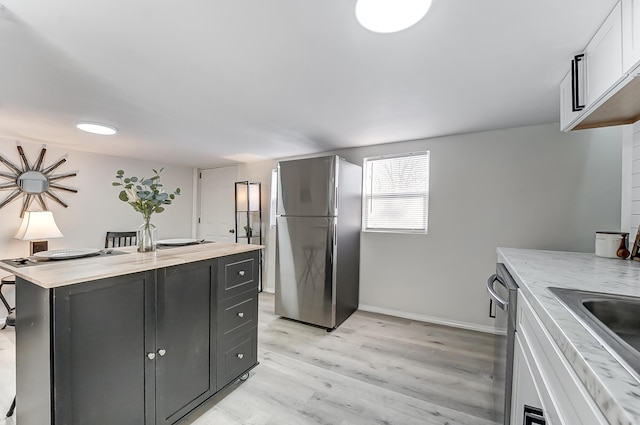 kitchen with wooden counters, stainless steel appliances, a center island, white cabinets, and light wood-type flooring