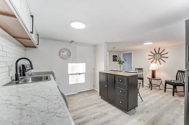 kitchen with tasteful backsplash, light hardwood / wood-style floors, a breakfast bar, and sink