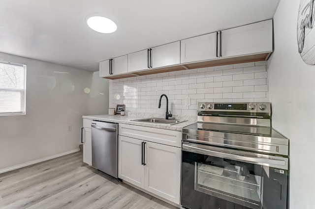 kitchen featuring tasteful backsplash, sink, white cabinets, and appliances with stainless steel finishes