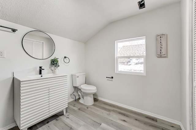 bathroom featuring lofted ceiling, toilet, a textured ceiling, vanity, and hardwood / wood-style flooring