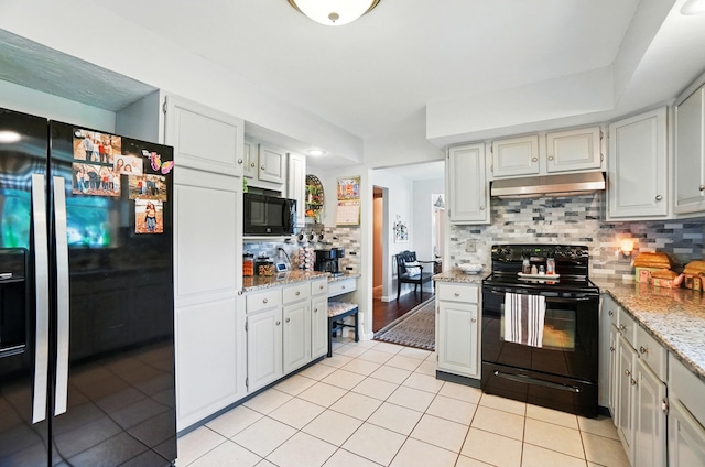 115 Deer Run Rd, Urbana, OH 43078 - kitchen featuring black appliances, under cabinet range hood, light tile patterned flooring, decorative backsplash, and light stone counters