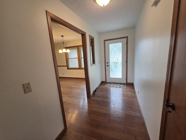 6708 Hillside Ct, Celina, OH 45822 - doorway to outside featuring dark wood-style floors, baseboards, a chandelier, and a textured ceiling