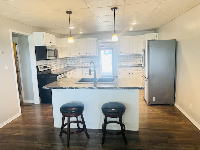 5319 Karafit Rd, Celina, OH 45822 - kitchen with stainless steel appliances, dark wood-style flooring, a center island with sink, white cabinets, and a drop ceiling