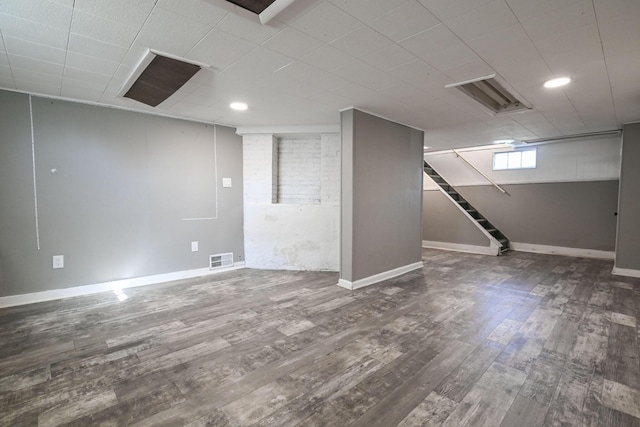 below grade area with visible vents, baseboards, stairway, recessed lighting, and wood finished floors