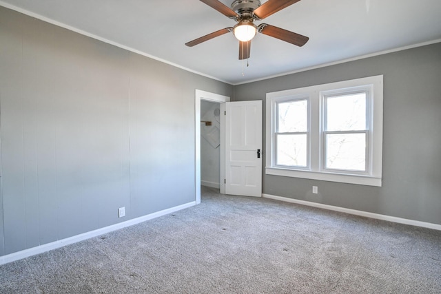 carpeted spare room with ceiling fan, baseboards, and ornamental molding