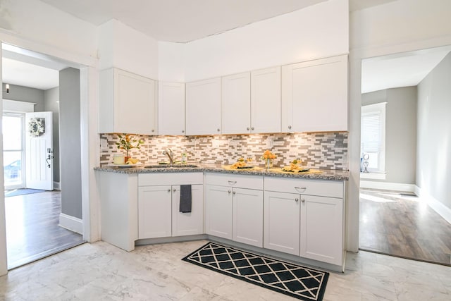 kitchen featuring decorative backsplash, marble finish floor, white cabinets, and a sink