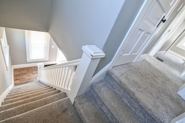 stairs featuring visible vents, baseboards, and carpet flooring