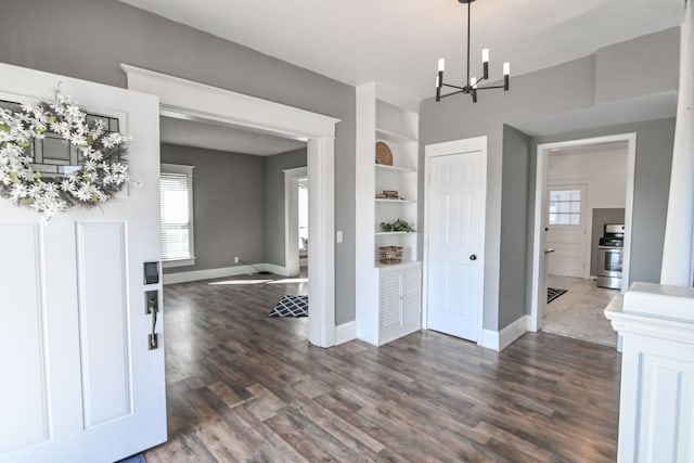 foyer featuring dark wood-type flooring, baseboards, and a chandelier