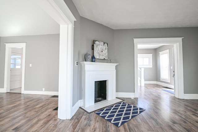 unfurnished living room with plenty of natural light, a fireplace, baseboards, and wood finished floors