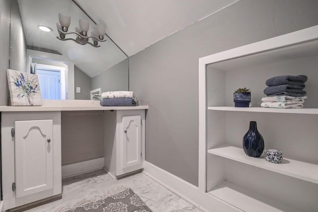 bathroom with marble finish floor, baseboards, and vaulted ceiling