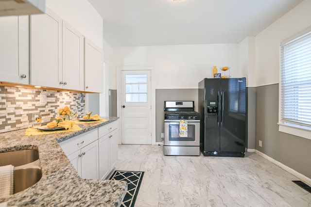 kitchen with black fridge with ice dispenser, a healthy amount of sunlight, stainless steel range with gas cooktop, and visible vents