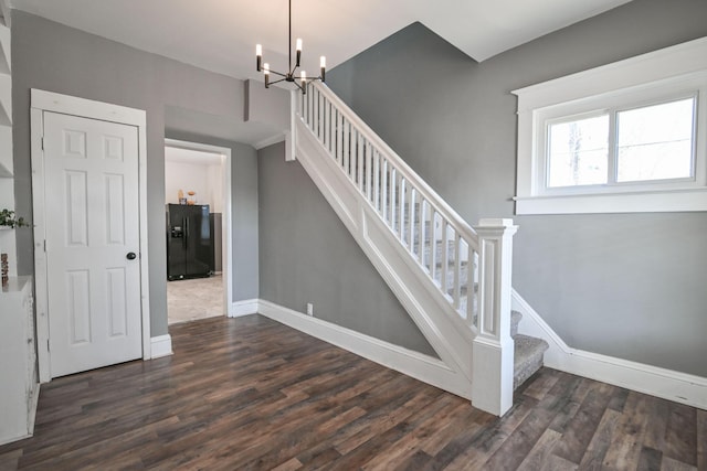 stairway with a notable chandelier, wood finished floors, and baseboards