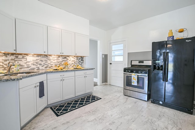 kitchen featuring stainless steel range with gas stovetop, black fridge, marble finish floor, and dark stone countertops