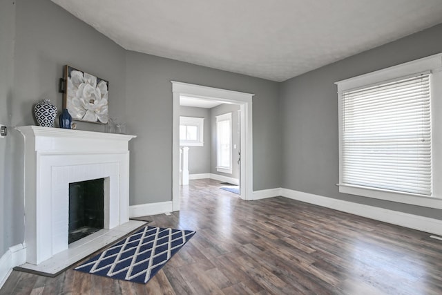 living room featuring baseboards, a brick fireplace, and wood finished floors