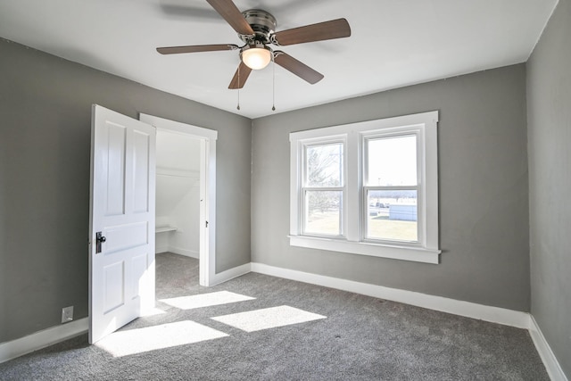 unfurnished bedroom with a walk in closet, baseboards, and carpet floors