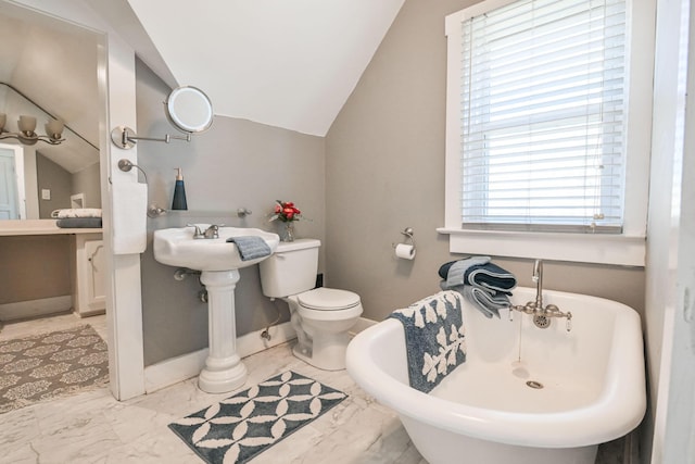 full bath with lofted ceiling, a freestanding tub, baseboards, and marble finish floor