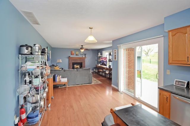 interior space with a fireplace, visible vents, light wood-style flooring, and ceiling fan