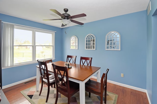 dining space featuring light wood-style floors, ceiling fan, baseboards, and visible vents