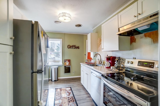 kitchen featuring white cabinets, appliances with stainless steel finishes, light countertops, under cabinet range hood, and a sink