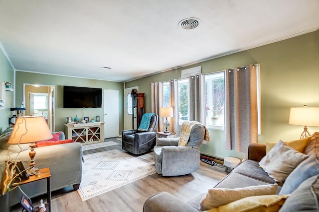 living room featuring plenty of natural light, crown molding, visible vents, and wood finished floors