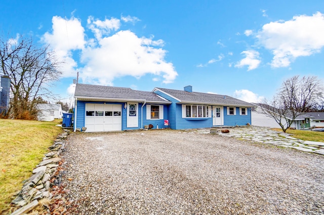 ranch-style house featuring a garage, a chimney, gravel driveway, and a front yard