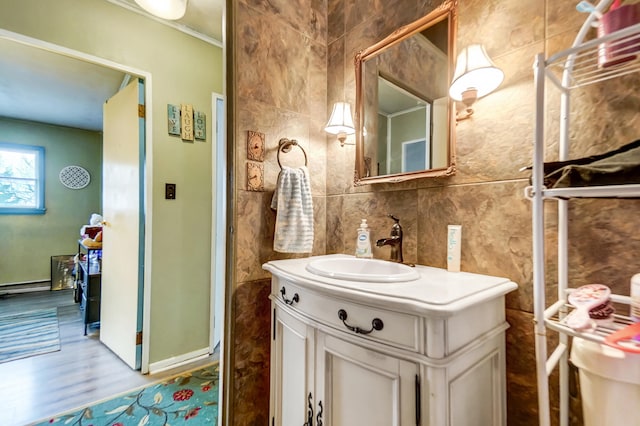 bathroom featuring wood finished floors, vanity, tile walls, tasteful backsplash, and walk in shower