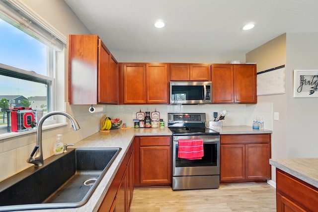 1087 Ayrshire Dr, Columbus, OH 43207 - kitchen featuring appliances with stainless steel finishes, a sink, tasteful backsplash, light wood-type flooring, and light countertops