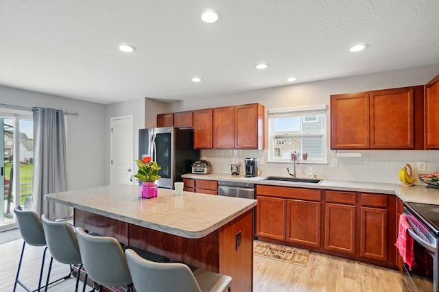 1087 Ayrshire Dr, Columbus, OH 43207 - kitchen featuring stainless steel appliances, a sink, a breakfast bar, light wood-type flooring, and light countertops
