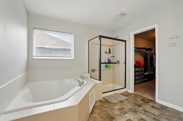 1087 Ayrshire Dr, Columbus, OH 43207 - full bathroom with a shower stall, a garden tub, a walk in closet, stone finish flooring, and baseboards