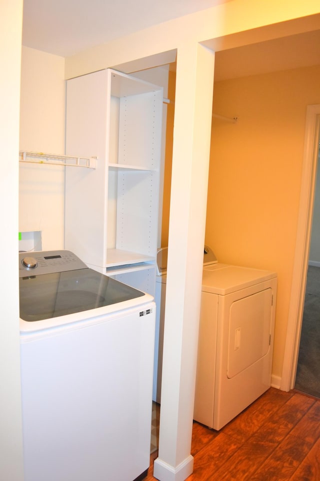 clothes washing area featuring dark wood-type flooring and washer and clothes dryer