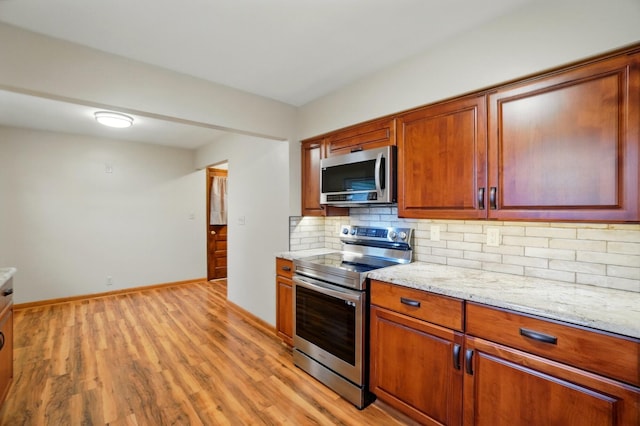 70 Helen St, Enon, OH 45323 - kitchen with stainless steel appliances, tasteful backsplash, light wood-style floors, light stone counters, and baseboards
