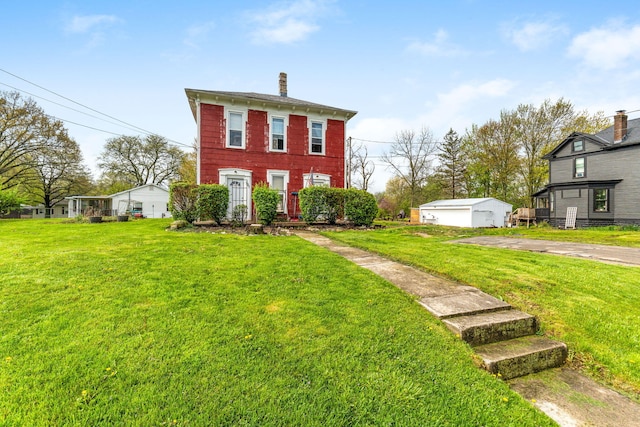 view of front facade featuring an outdoor structure, a front lawn, and a chimney