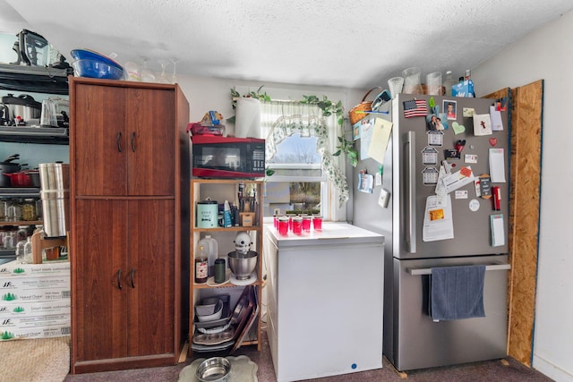 kitchen featuring carpet, freestanding refrigerator, and a textured ceiling