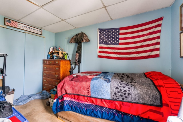bedroom featuring a drop ceiling, a closet, and carpet floors