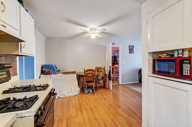 kitchen with light wood-type flooring, white gas range, white cabinets, and light countertops