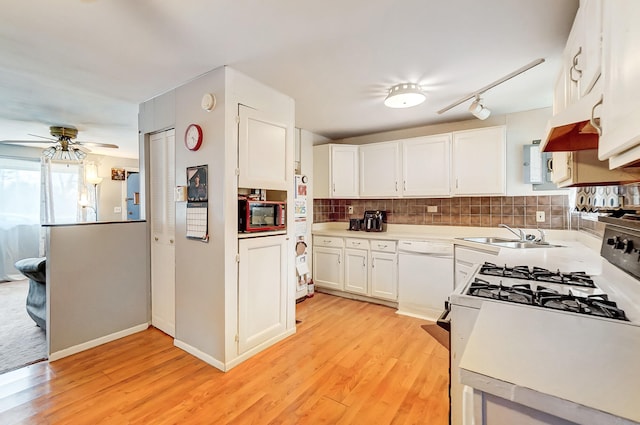 kitchen with white appliances, tasteful backsplash, light wood-type flooring, white cabinetry, and a sink