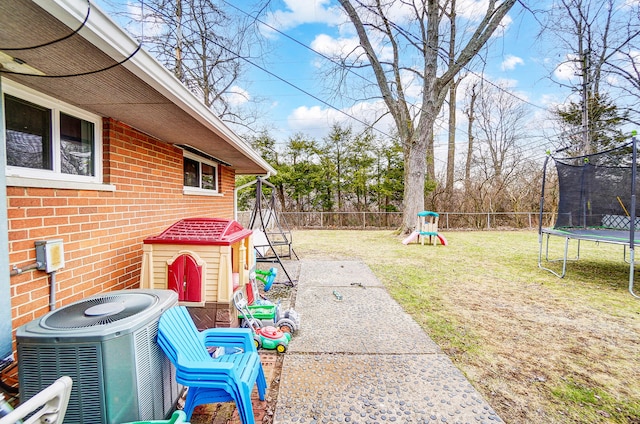 view of yard featuring a trampoline, a fenced backyard, and central AC unit