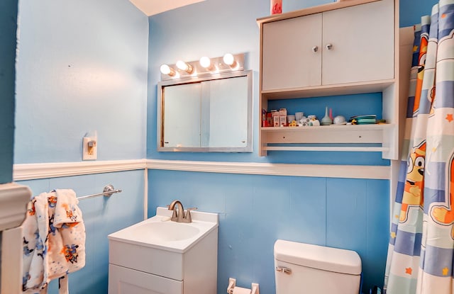 full bathroom with toilet, a wainscoted wall, a shower with curtain, and vanity