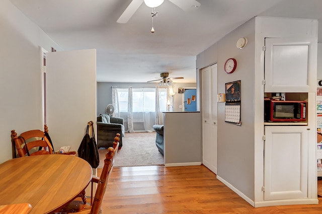 dining area featuring light wood-style floors, baseboards, and a ceiling fan