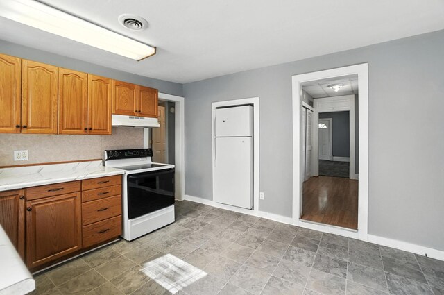 224 Monroe St, Delphos, OH 45833 - kitchen with white electric range, under cabinet range hood, light stone countertops, and brown cabinetry